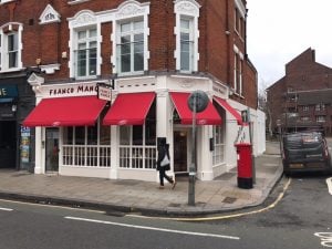 Across the street view of 3 red restaurant awnings of Franco Manca in Putney