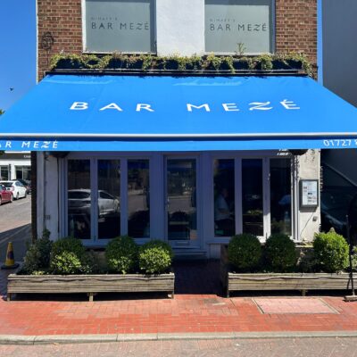 Wide blue restaurant awning as seen across street